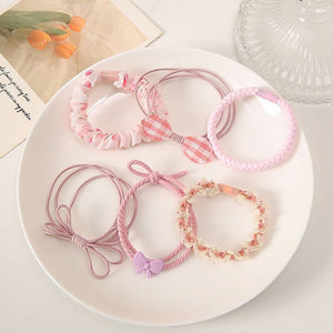 Flat lay of 6 pink flower hair ties in pastel pink 
